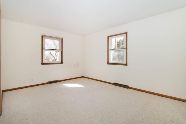 carpeted empty room featuring baseboards and visible vents