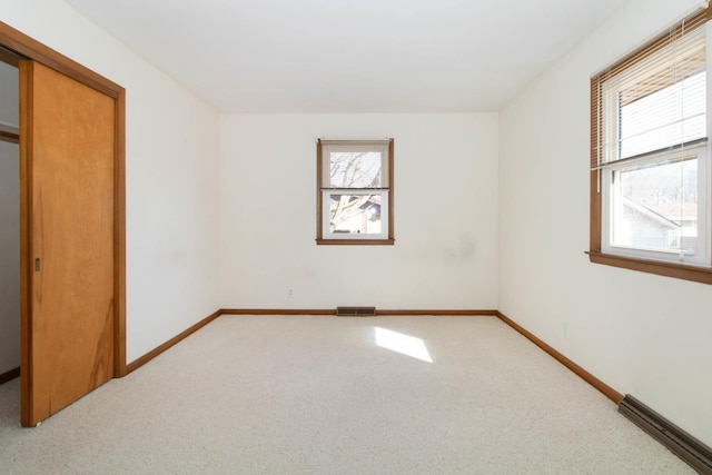 unfurnished bedroom featuring carpet, multiple windows, visible vents, and baseboards