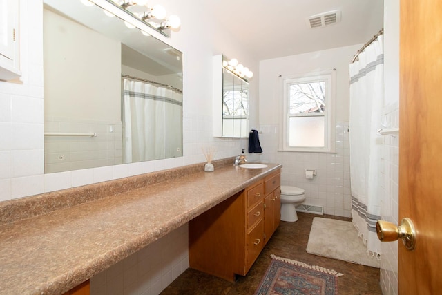 bathroom with toilet, vanity, visible vents, and tile walls