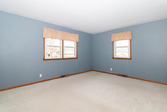 carpeted spare room with visible vents and baseboards