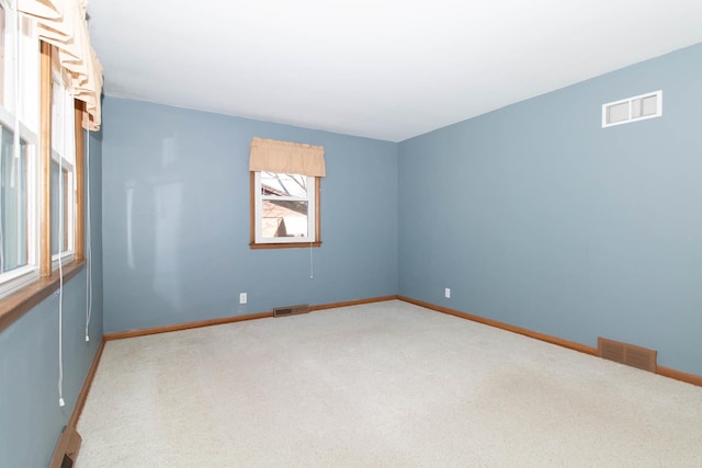 empty room featuring carpet, visible vents, and baseboards