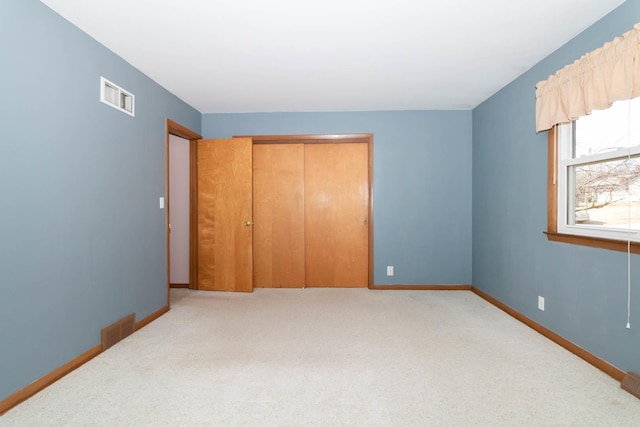 unfurnished bedroom featuring light carpet, a closet, visible vents, and baseboards