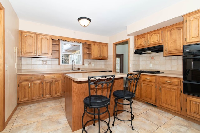 kitchen featuring under cabinet range hood, a kitchen island, a sink, light countertops, and open shelves