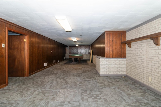 interior space with brick wall, wood walls, carpet, and visible vents