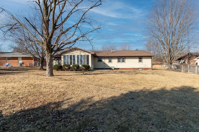 rear view of house with fence and a yard