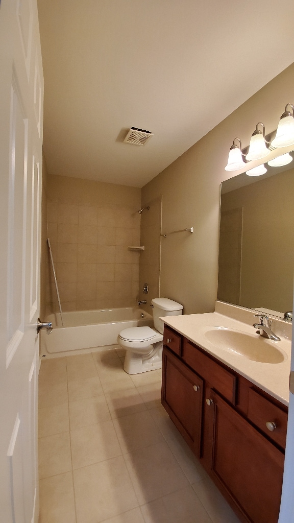 full bath featuring toilet, vanity, visible vents, tile patterned floors, and washtub / shower combination