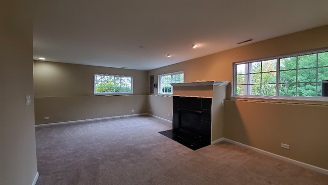 unfurnished living room with baseboards, visible vents, carpet flooring, and a tile fireplace