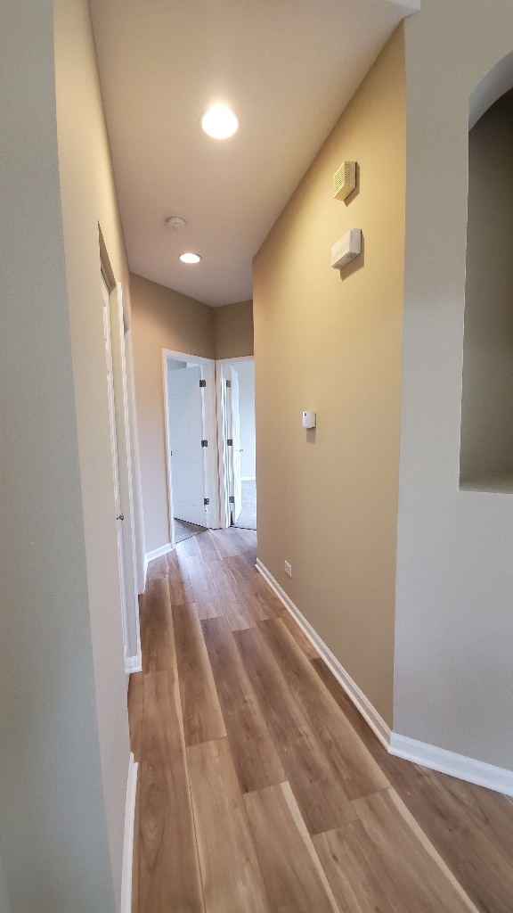 hallway featuring recessed lighting, baseboards, and wood finished floors