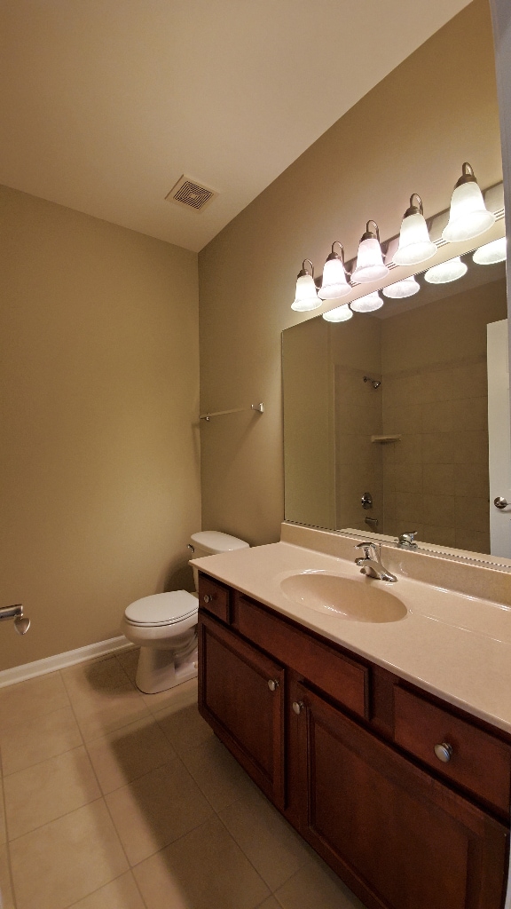 full bathroom with a shower, visible vents, toilet, vanity, and tile patterned floors