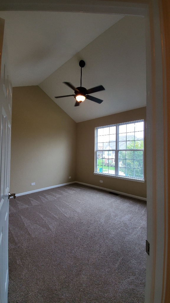 unfurnished room featuring carpet floors, ceiling fan, baseboards, and vaulted ceiling