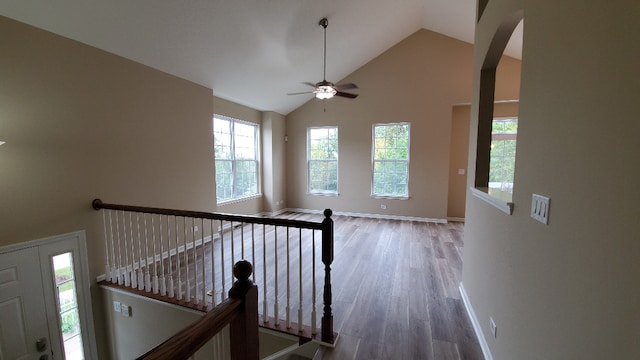 stairway with baseboards, arched walkways, ceiling fan, and wood finished floors