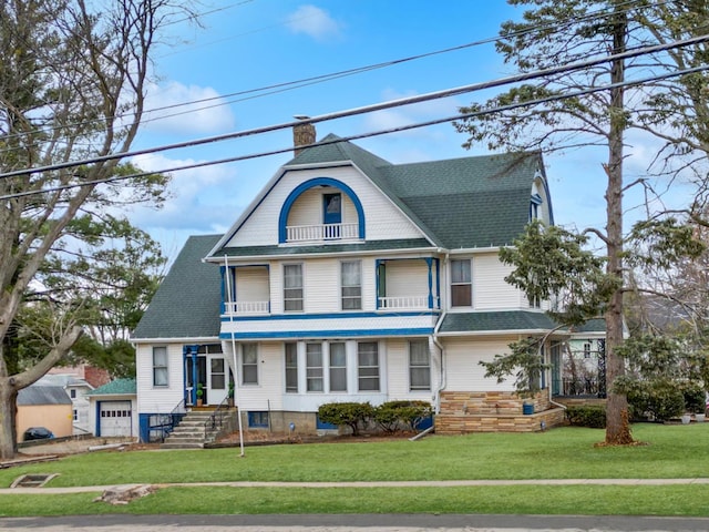 view of front facade with a chimney, a front yard, and a balcony