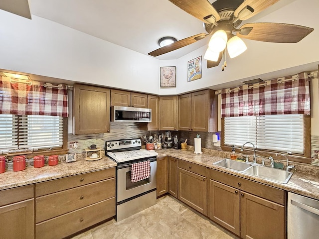 kitchen with stainless steel appliances, a sink, backsplash, and a ceiling fan