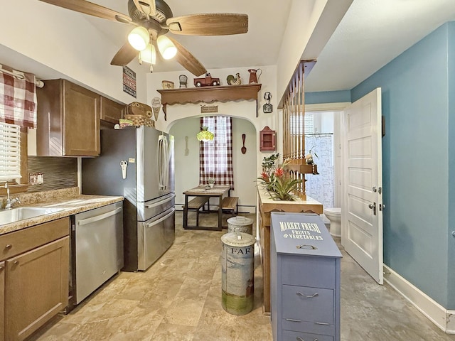 kitchen with baseboards, a ceiling fan, appliances with stainless steel finishes, light countertops, and a sink