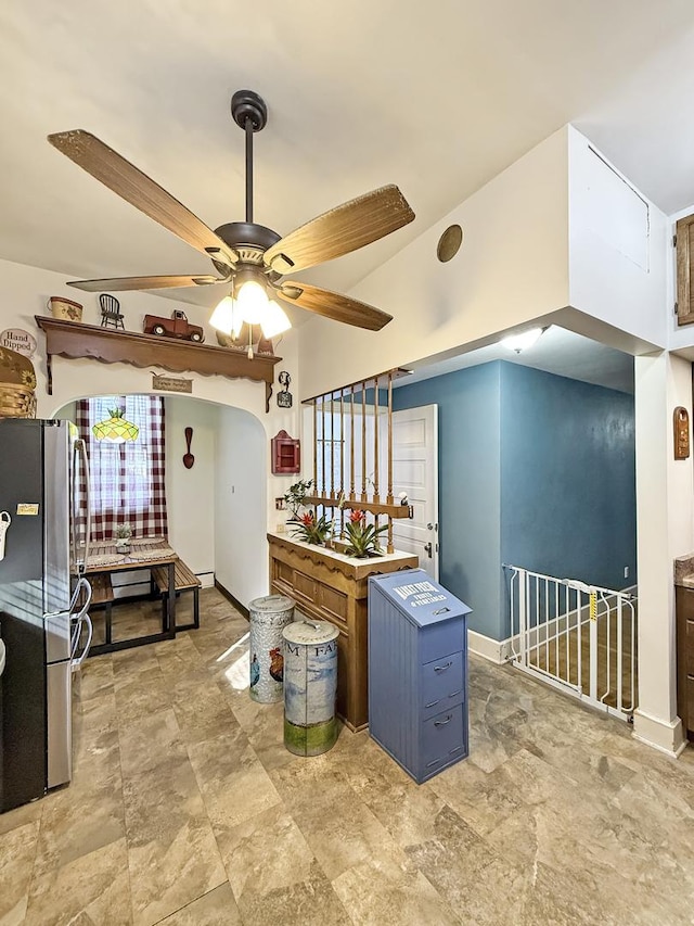 kitchen with ceiling fan, arched walkways, baseboards, vaulted ceiling, and freestanding refrigerator