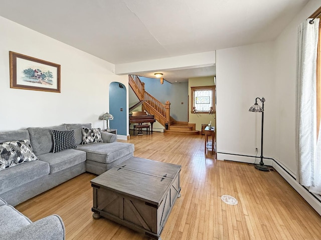 living area featuring arched walkways, stairway, and light wood-type flooring