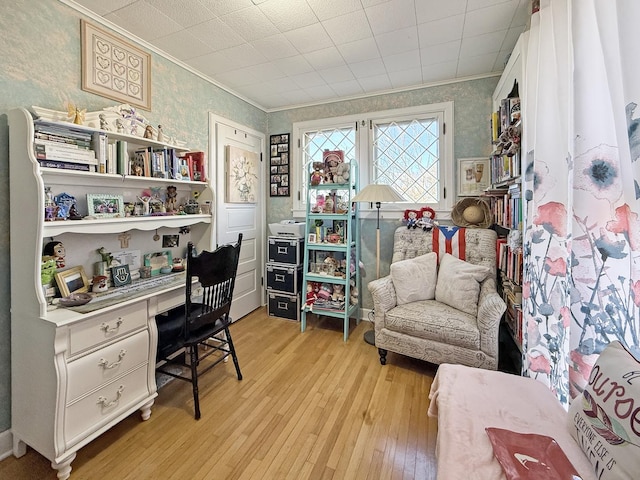 home office featuring light wood-style floors, wallpapered walls, crown molding, and built in study area