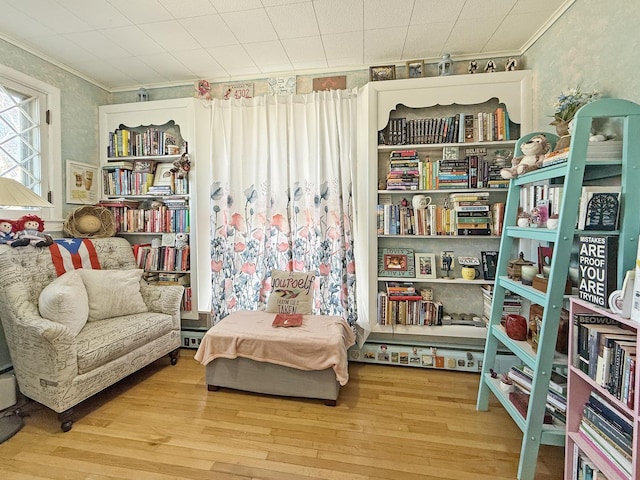 living area with ornamental molding, a baseboard heating unit, and wood finished floors