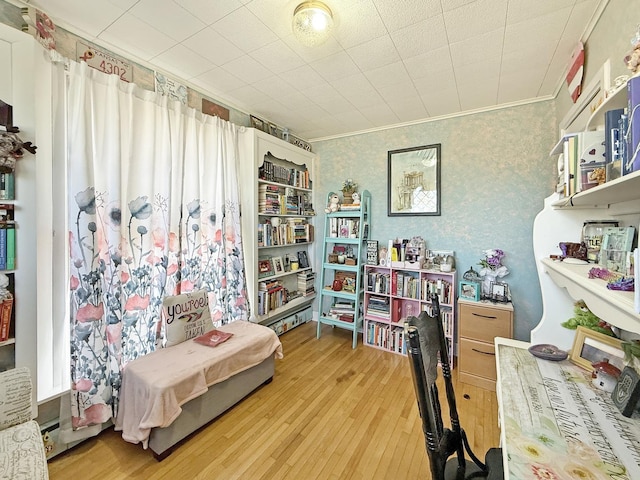 interior space with wallpapered walls, wood finished floors, and crown molding