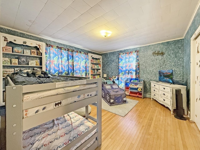 bedroom featuring hardwood / wood-style flooring, wallpapered walls, and crown molding