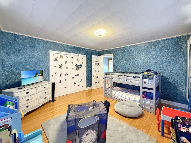 bedroom featuring wallpapered walls, crown molding, and wood finished floors