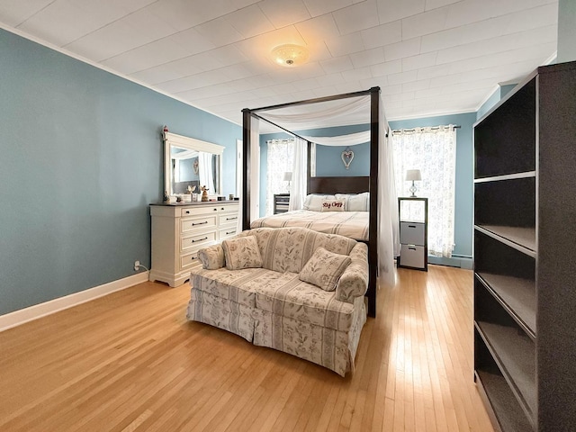 bedroom featuring light wood finished floors, baseboards, and ornamental molding