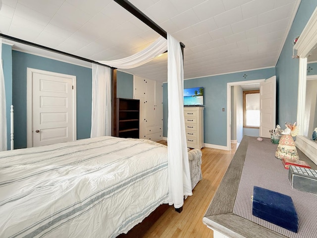 bedroom with crown molding, baseboards, and wood finished floors