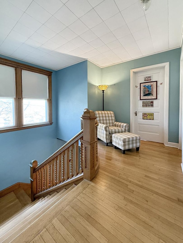 living area with wood-type flooring, baseboards, and an upstairs landing