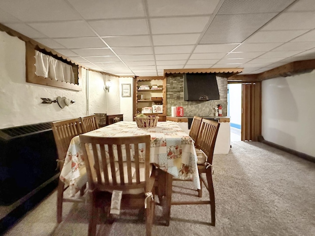 dining area with baseboards, built in shelves, a drop ceiling, and light colored carpet