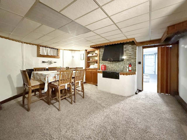 dining area with baseboards, light carpet, and a drop ceiling