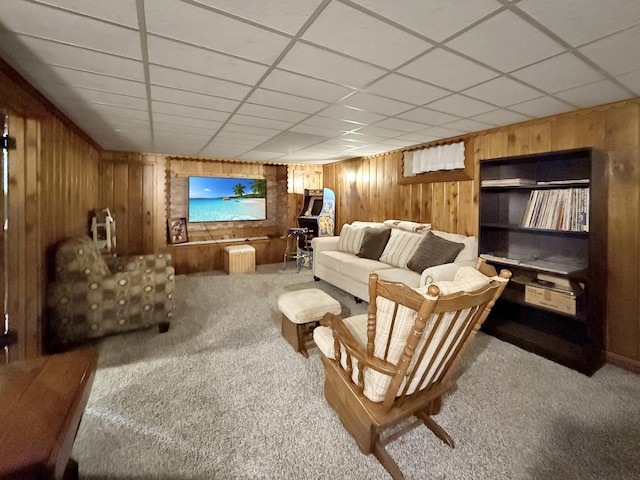 living area with carpet floors, wooden walls, and a drop ceiling