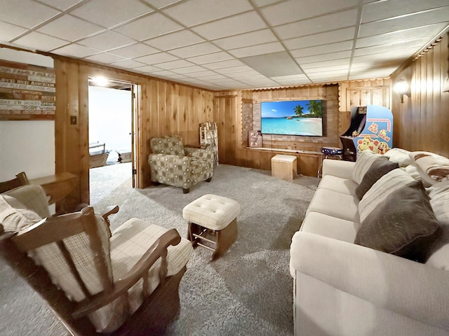 living area featuring carpet floors, wooden walls, a baseboard heating unit, and a paneled ceiling