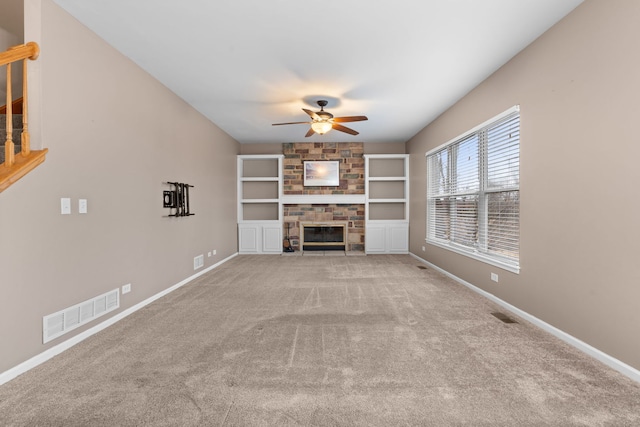 unfurnished living room featuring carpet floors, a fireplace, a ceiling fan, visible vents, and baseboards