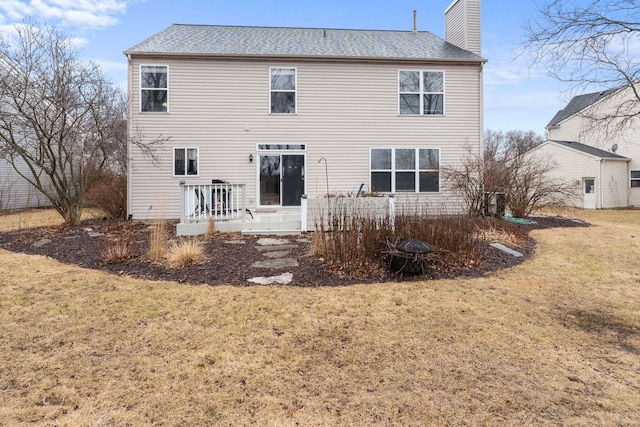 rear view of property with a chimney and a lawn