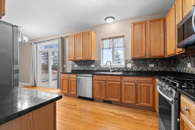 kitchen featuring stainless steel appliances, visible vents, backsplash, light wood-style flooring, and a sink