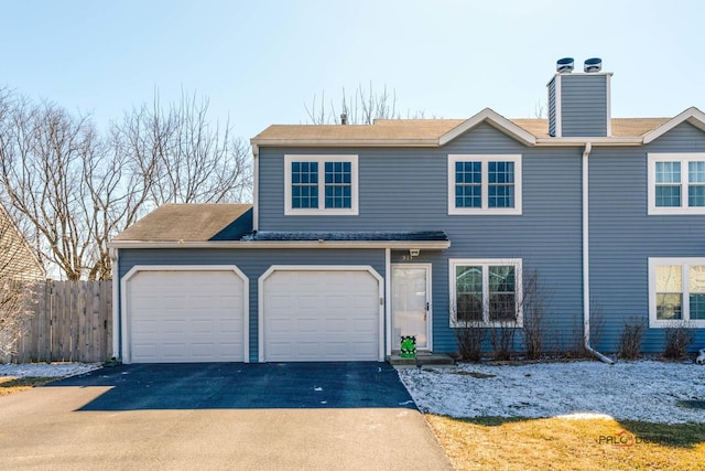 view of front of house featuring driveway, a chimney, and fence