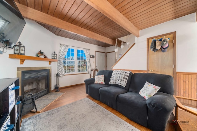 living area with wooden ceiling, wood finished floors, a tiled fireplace, and beamed ceiling