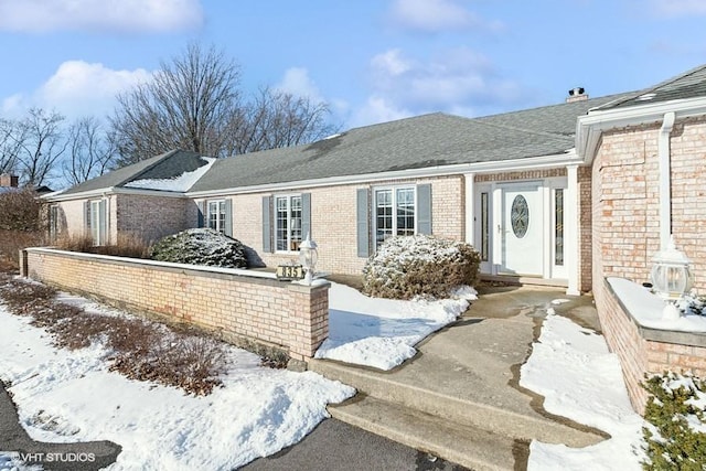 view of front of property featuring a shingled roof and brick siding