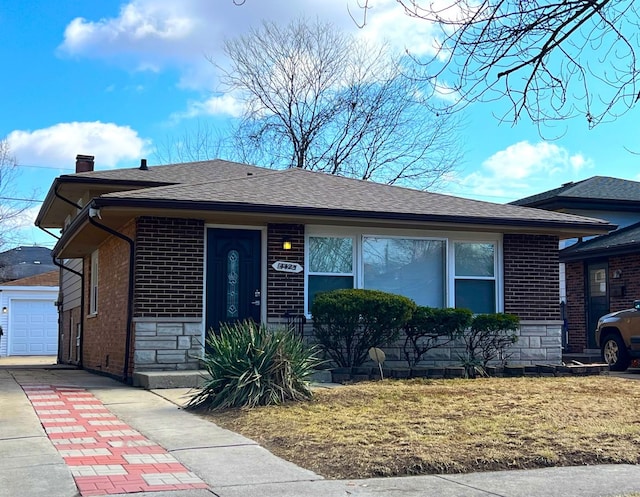 single story home with a garage, stone siding, roof with shingles, an outbuilding, and brick siding