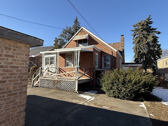 bungalow with a chimney and brick siding