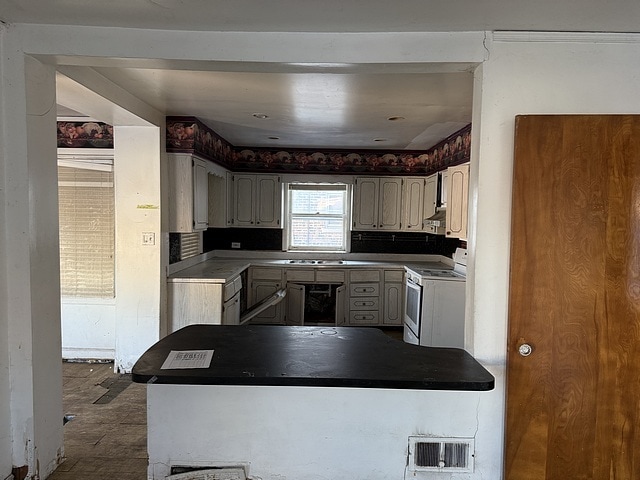 kitchen with a peninsula, white gas range, visible vents, and under cabinet range hood