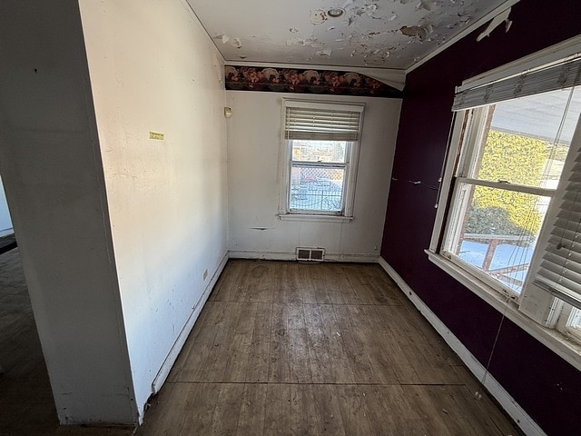 spare room featuring ornamental molding, visible vents, baseboards, and hardwood / wood-style flooring