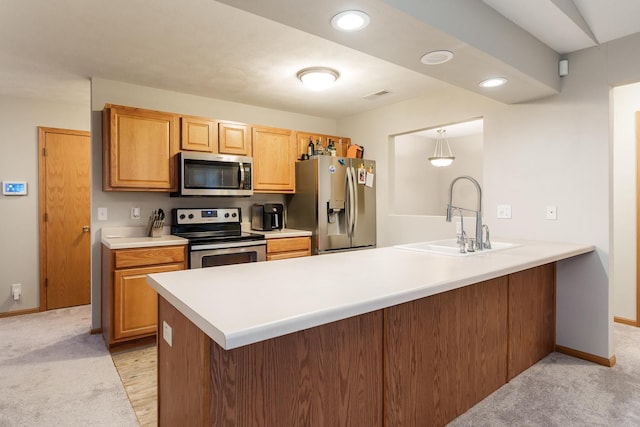 kitchen featuring visible vents, a peninsula, stainless steel appliances, light countertops, and a sink