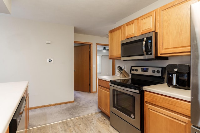 kitchen featuring stainless steel appliances, light countertops, light wood-style floors, and baseboards