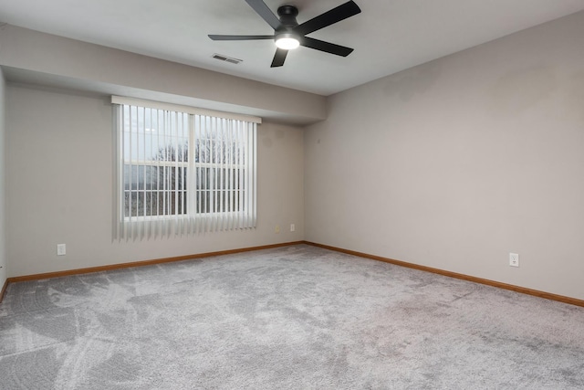 carpeted empty room featuring baseboards, visible vents, and ceiling fan