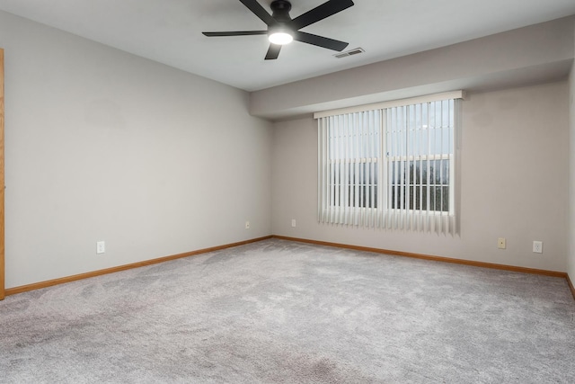 carpeted empty room featuring baseboards, visible vents, and a ceiling fan