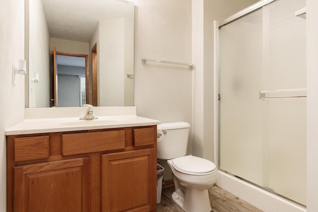 bathroom featuring vanity, wood finished floors, a shower stall, and toilet