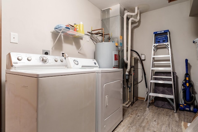 washroom with light wood-type flooring, laundry area, water heater, and separate washer and dryer