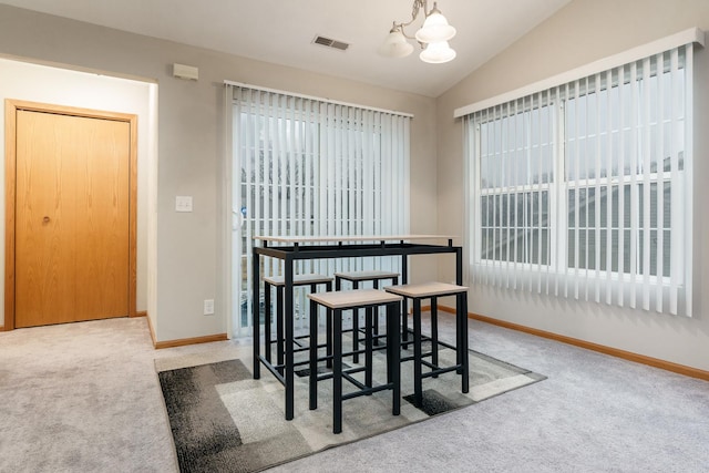 carpeted dining space featuring visible vents, vaulted ceiling, a chandelier, plenty of natural light, and baseboards