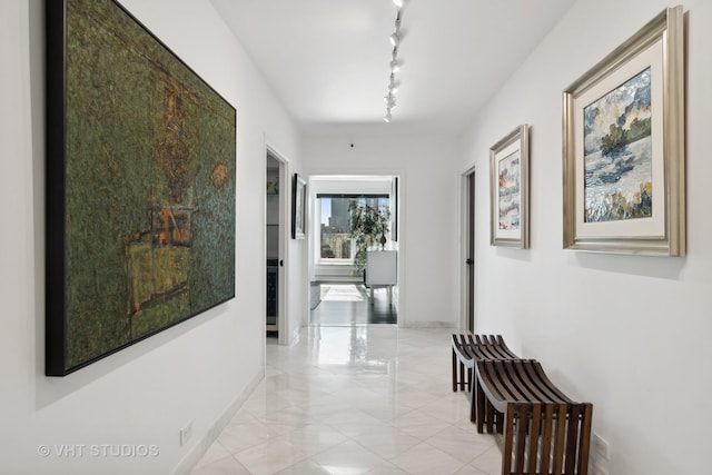 corridor featuring baseboards and track lighting